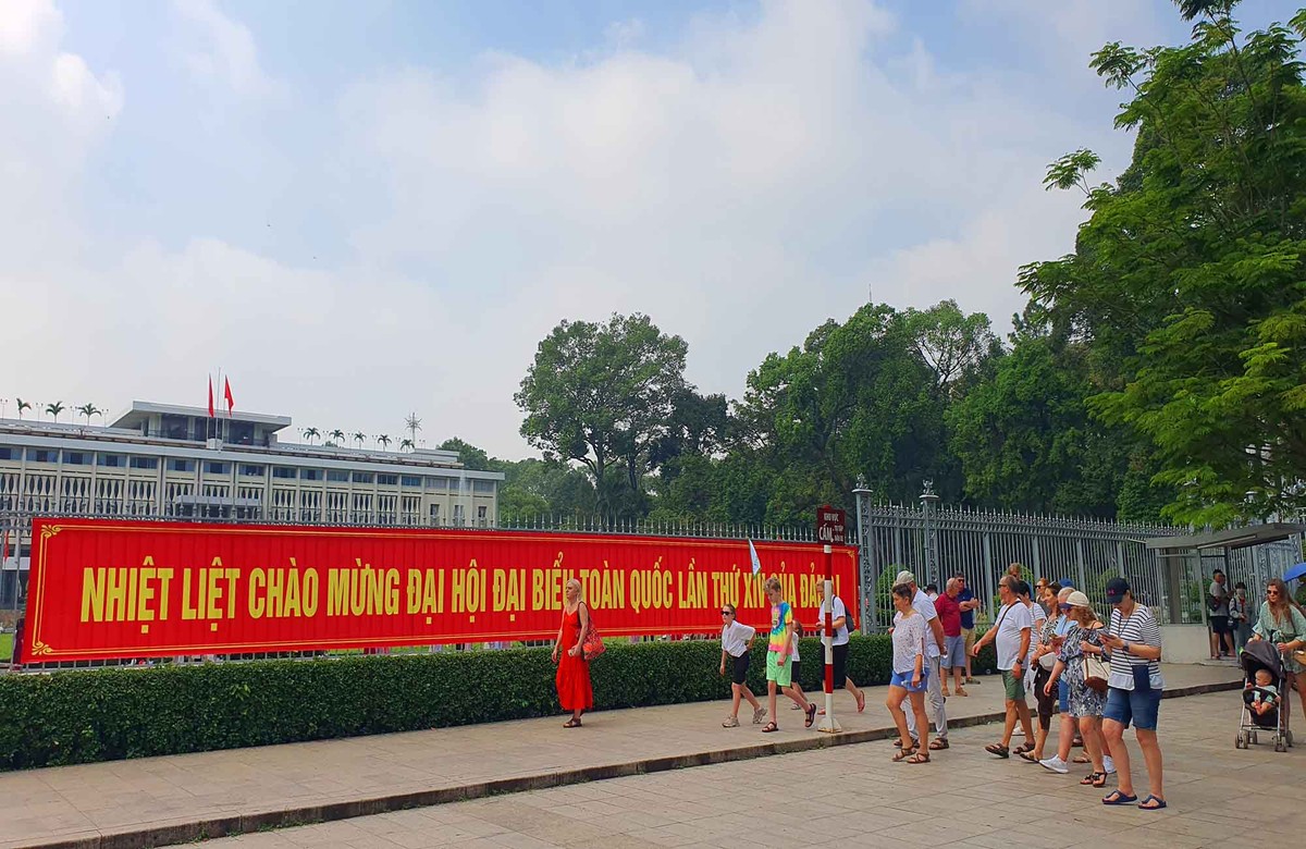 Khách quốc tế và người dân dạo bước qua khu vực treo băng rôn, pano chào mừng Đại hội Đảng, ghi lại những khoảnh khắc về không khí chuẩn bị cho sự kiện chính trị quan trọng của đất nước.