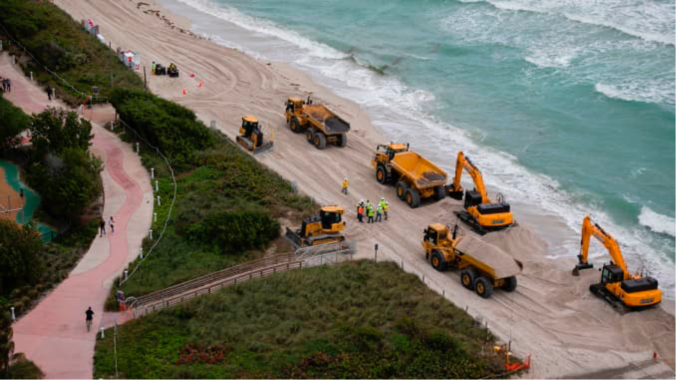 Hàng chục xe tải đổ hàng trăm nghìn tấn cát trên Bãi biển Miami, một phần trong các biện pháp của chính phủ Mỹ nhằm bảo vệ các điểm du lịch của Florida trước tác động của biến đổi khí hậu. Ảnh: AFP