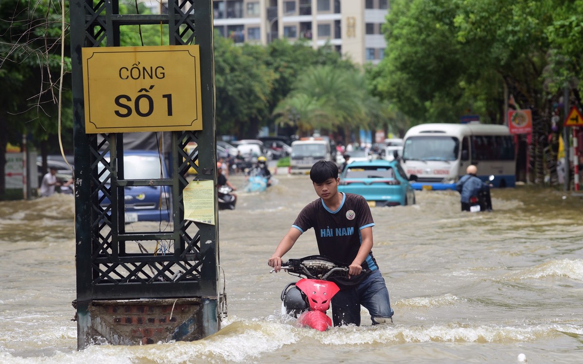 Các con đường bên trong KĐT Lê Trọng Tấn - Geleximco đều ngập chìm trong nước, đặc biệt tại khu vực cổng ra vào. Người dân muốn di chuyển chỉ có cách dắt xe.