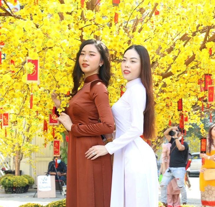 Các thiếu nữ tạo dáng bên gốc mai cổ thụ tại lễ hội tết Việt