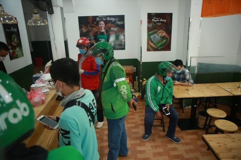 Shipper đợi lấy đồ ăn đi giao ở đường Duy Tân, quận Cầu Giấy. (Ảnh: Phương Linh)