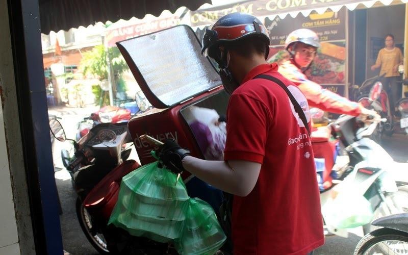 Anh Hoàng Văn Quý nhận hàng từ quán cơm tại Duy Tân- Cầu Giấy để giao qua đường Phạm Văn Bạch cho khách. (Ảnh: Phương Linh)