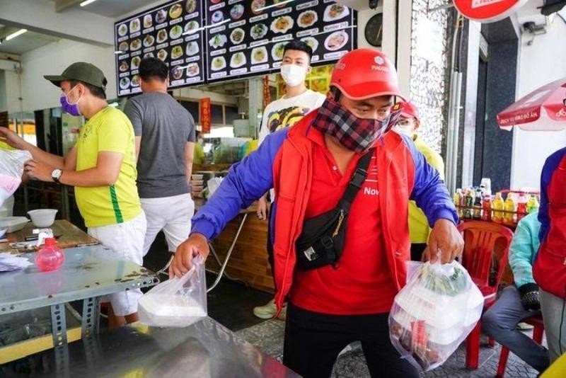 Shipper vội vã đi giao đồ cho khách giữa trưa nắng. (Ảnh: Phương Linh)