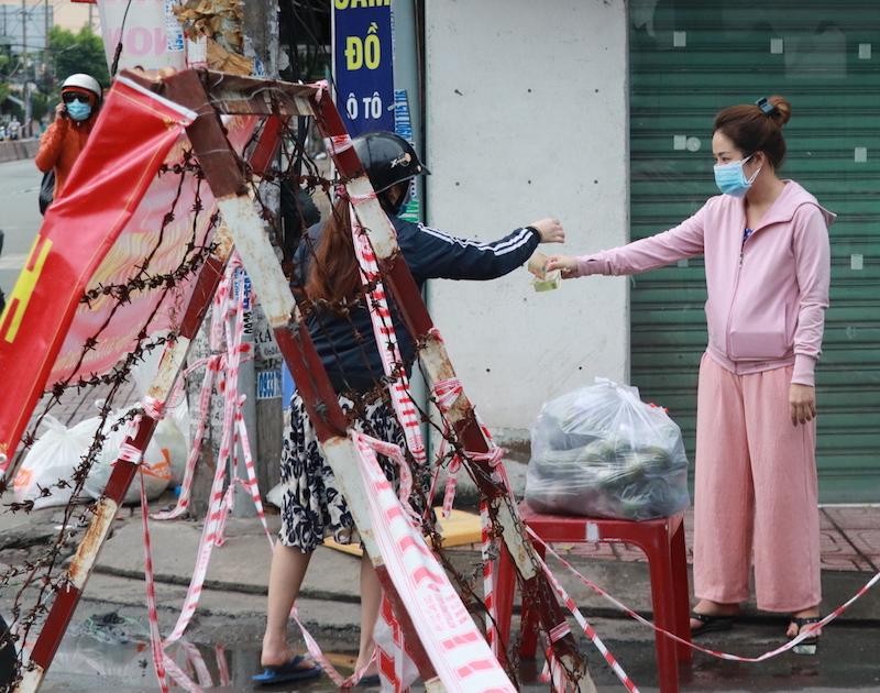 Người dân trong khu vực phong toả tại đường Bùi Văn Ba, quận 7 trả tiền, nhận hàng hoá (Ảnh: Thị Hồng).