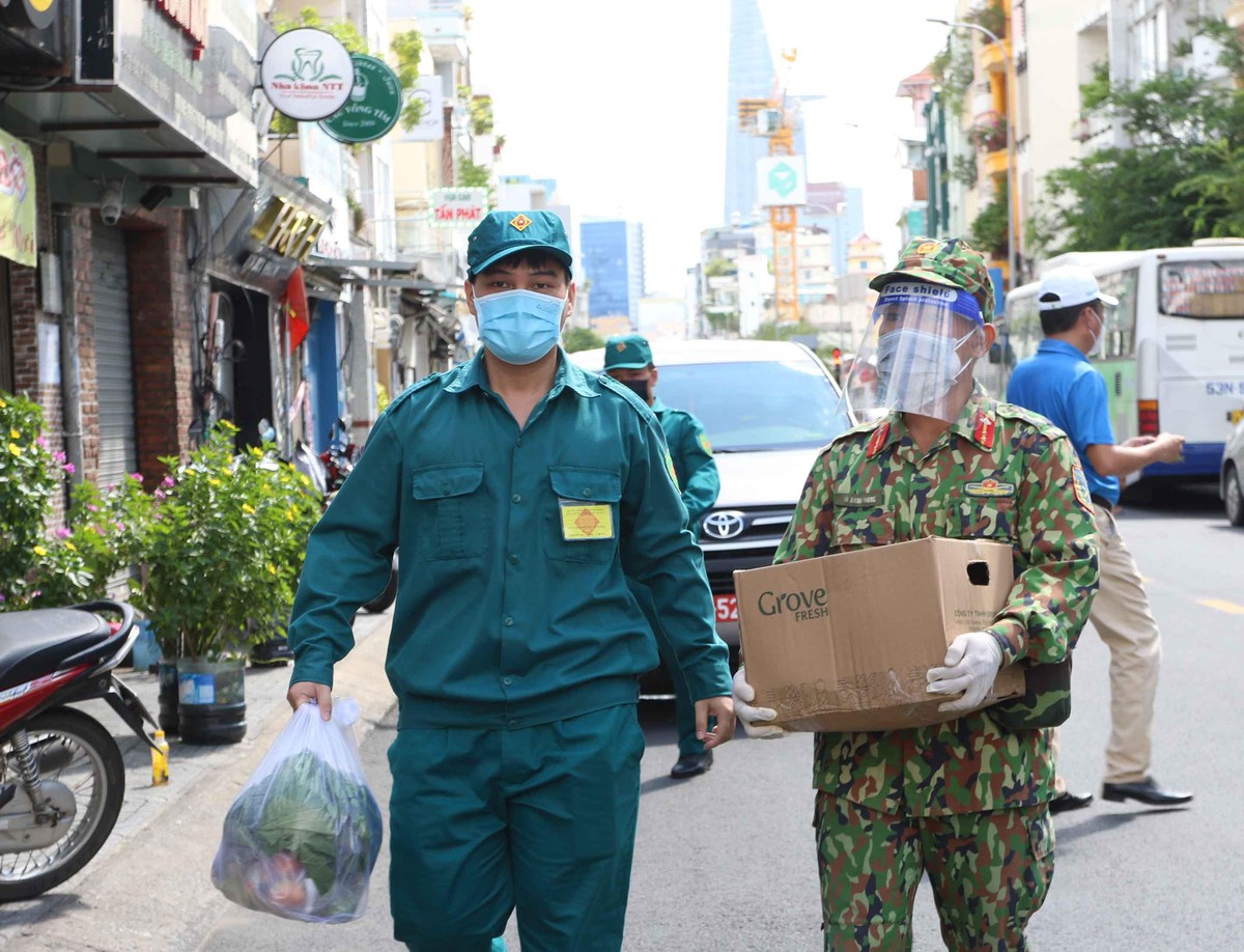 Lực lượng đi chợ thay người dân tìm địa chỉ nhà để giao hàng. (Ảnh: Lê Toàn).