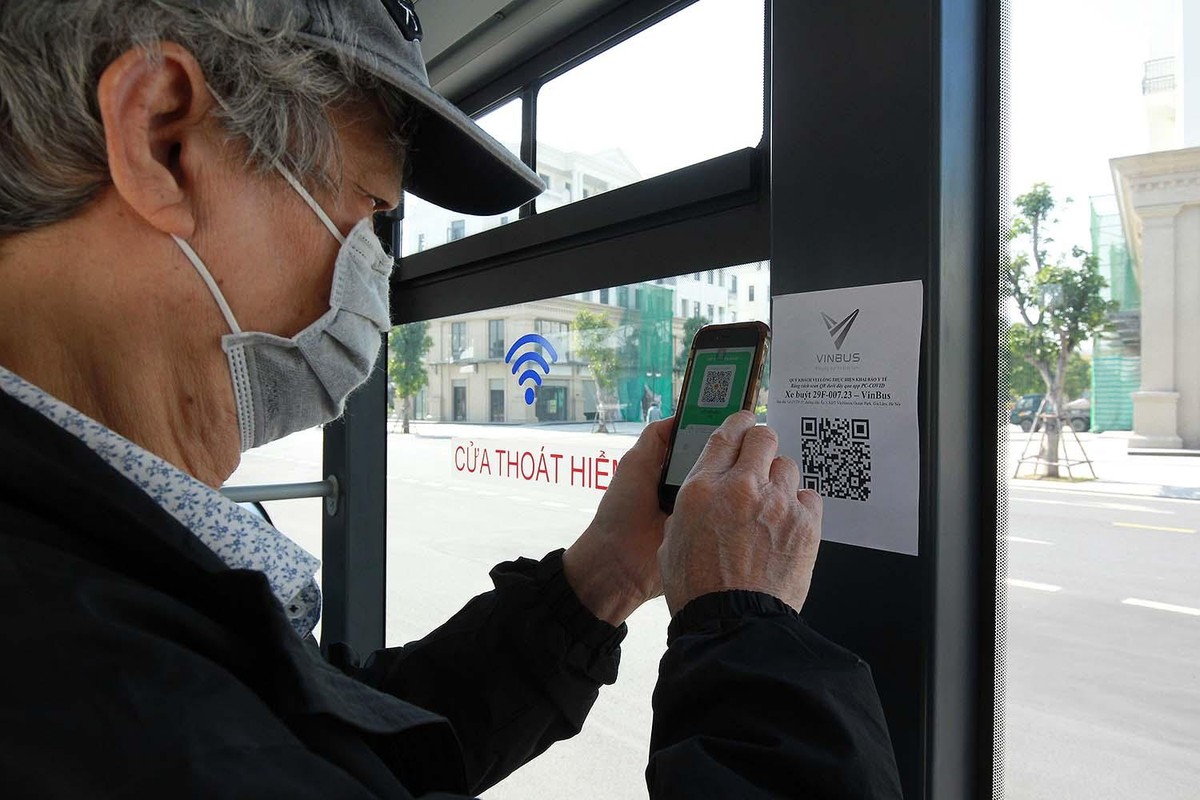 Khách lên xe buýt được nhân viên nhắc thực hiện quét mã QR khai báo phục vụ công tác phòng, chống dịch