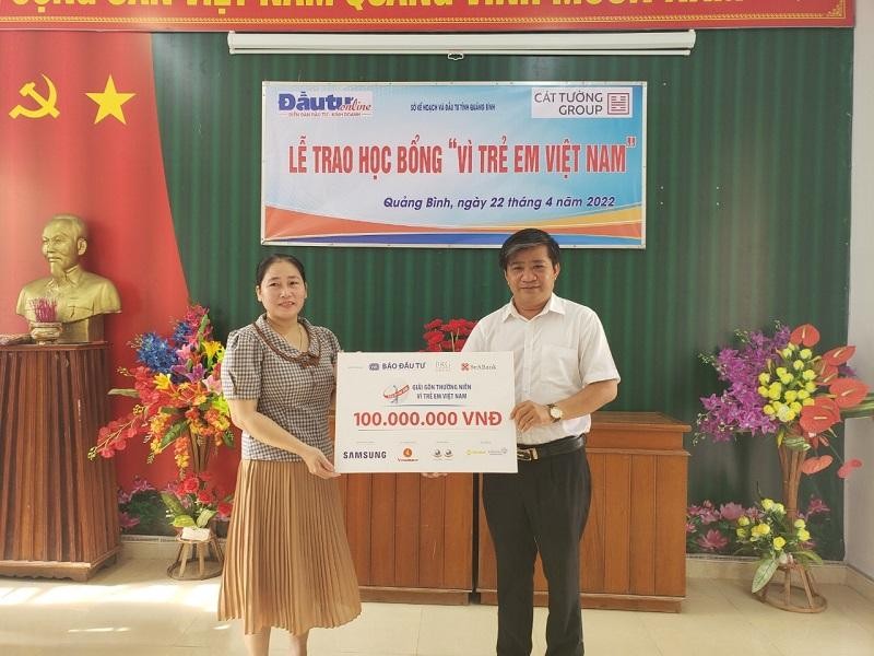 Nhà báo Hoàng Kim Thủy, Trưởng Văn phòng Đại diện Báo Đầu tư tại khu vực miền Trung - Tây Nguyên (phải) trao bảng tượng trưng 100 suất học bổng cho bà Lê Tuyết Nhung, Hiệu trưởng Trường THCS Phú Thuỷ.