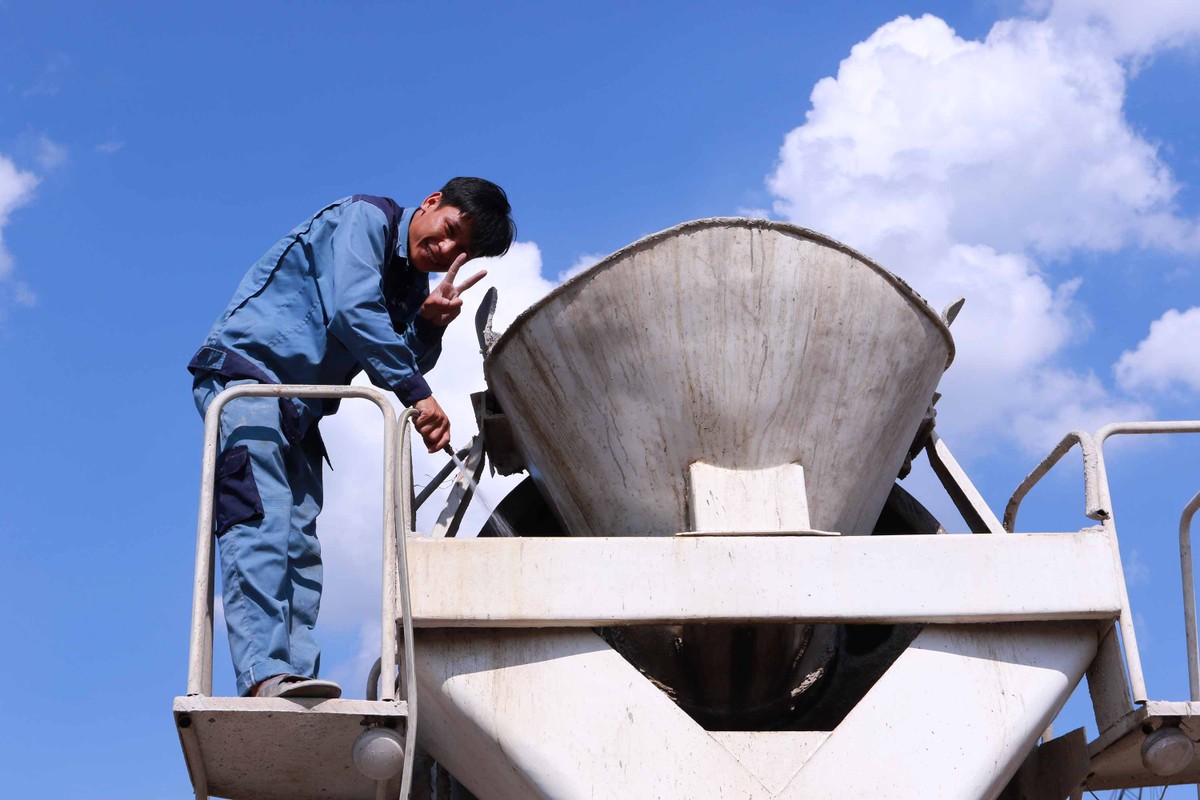 Công nhân Trần Xuân Cường, 30 tuổi quê Nghệ An vừa vệ sinh phễu rót bê tông vừa cho biết, từ sáng đến trưa Cường đã vận chuyển được 4 chuyến xe bê tông tới công trình.