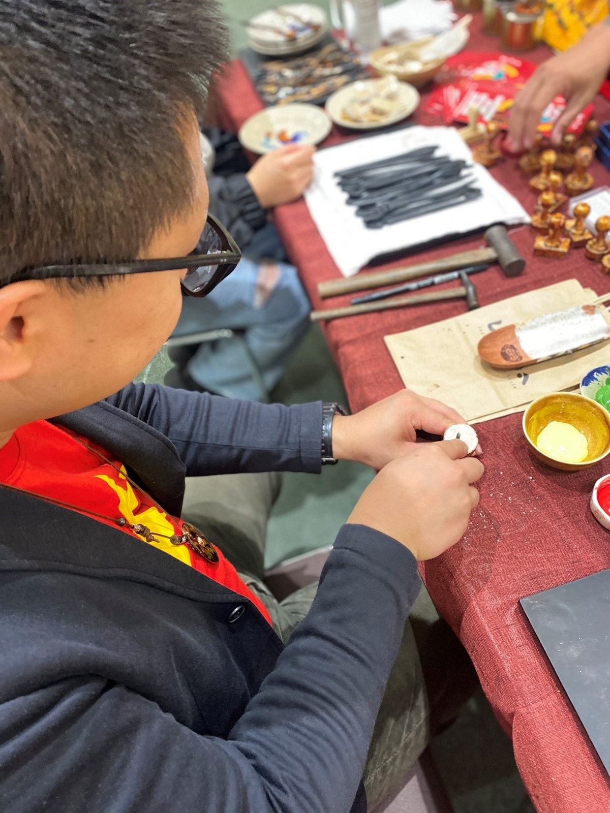 Khách trải nghiệm thực hành sơn mài khắc trên con dấu. (Ảnh: Bộ Ngoại giao Việt Nam)