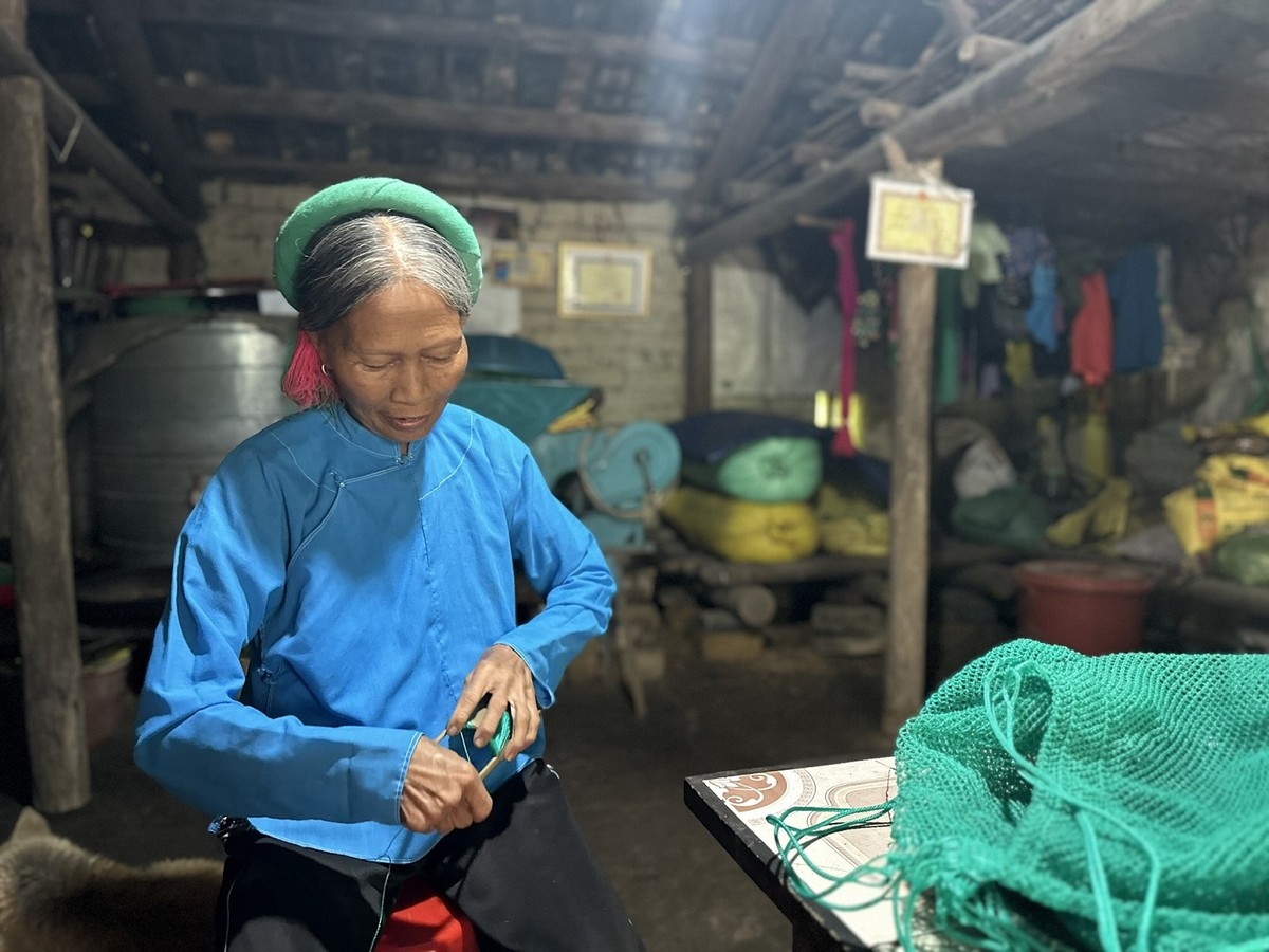 Bà Nình Móc Mầu, 76 tuổi chủ nhân căn nhà có niên đại trên nửa thế kỷ ở thôn Khe Lục. Nhiều du khách đến thăm quan căn nhà cổ nơi bà đang sinh sống và mua sản phẩm đan thủ công do chính tay bà đan móc. Ảnh: Quỳnh Nga