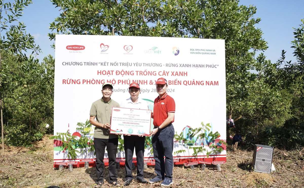 Ông Trần Đình Quân, Chủ tịch Hội đồng Thành viên Dai-ichi Life Việt Nam kiêm Chủ tịch Quỹ Vì cuộc sống tươi đẹp (áo đỏ) trao biểu trưng số tiền tài trợ 500 triệu đồng trồng 10.000 cây lim xanh cho Đại diện Ban Quản lý Rừng phòng hộ Phú Ninh và Green Việt