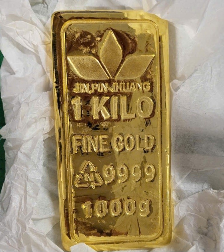 Tang vật là miếng kim loại màu vàng, bên trên có khắc chữ “JIN, PIN-JHUANG 1 KILO FINE GOLD 9999 1000g”. (Ảnh đơn vị cung cấp).