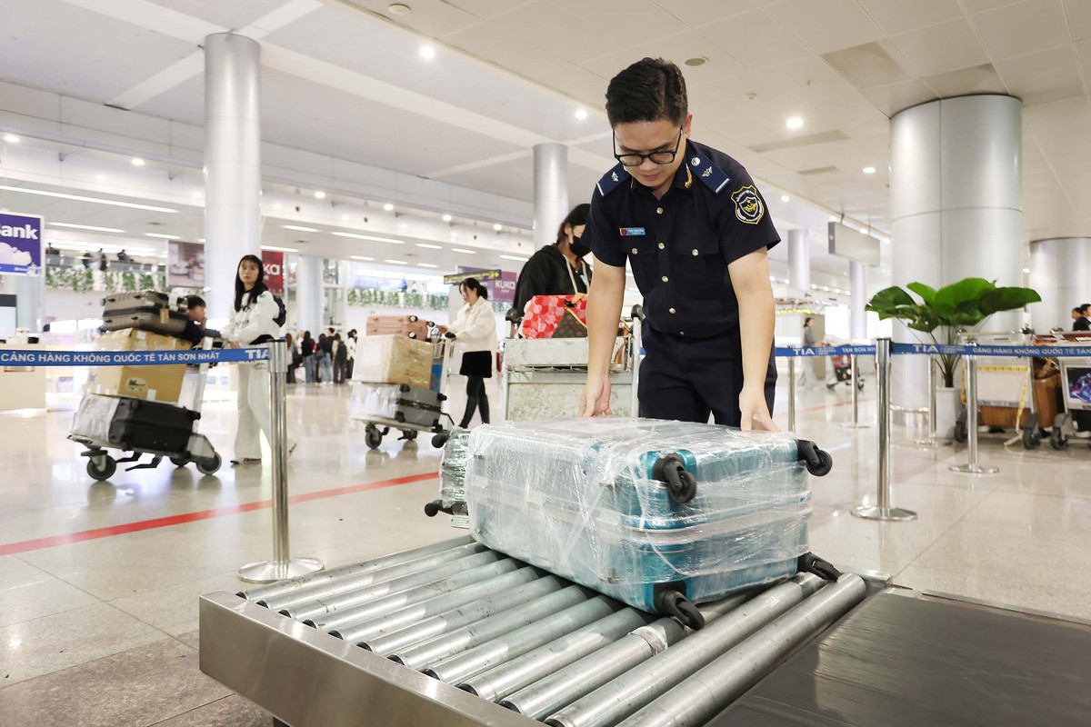 Nhân viên hải quan Phạm Thành Công giúp hành khách nữ đưa hành lý vào kiểm tra.