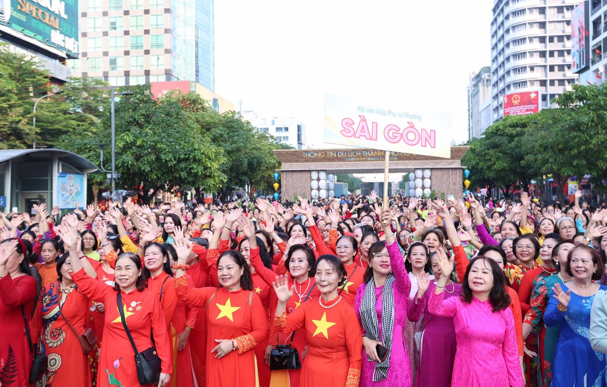 Trên các tuyến đường quen thuộc, từ những cô gái trẻ đến các cô, các bà lớn tuổi đều rạng rỡ bước đi trong nắng sớm tháng Ba. Những tà áo dài nhiều sắc màu hòa cùng tiếng cười, tiếng vỗ tay và những lá cờ nhỏ tung bay, tạo nên một “dòng sông áo dài” sống động giữa lòng thành phố.