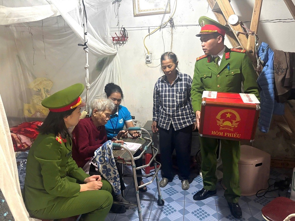 Lực lượng Công an xã Hợp Tiến đã phối hợp với Tổ bầu cử số 12 tổ chức mang hòm phiếu phụ đến tận nhà Mẹ Việt Nam Anh hùng Phan Thị Cẳm (97 tuổi) và các cử tri cao tuổi, sức khỏe yếu, không thể đến khu vực bỏ phiếu, nhằm bảo đảm mọi công dân đều được thực hiện quyền và nghĩa vụ thiêng liêng của mình. Ảnh: ANHP