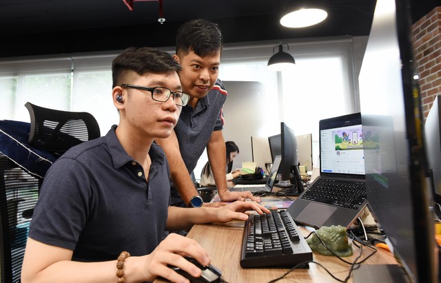 Anh Sơn - &quot;cha đẻ&quot; Bò và Gấu (người đứng) trao đổi công việc với Hà - trưởng nhóm content. Ảnh: Dũng Minh.