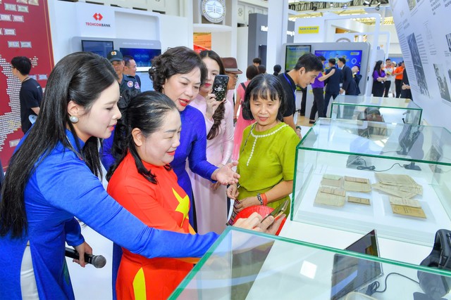 Thống đốc NHNN Nguyễn Thị Hồng hướng dẫn khách tham quan thao tác quét mã QR để đọc các thông tin về lịch sử ngành Ngân hàng Việt Nam...