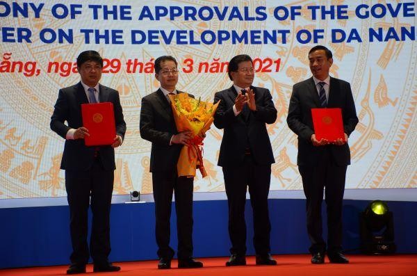 Phó Thủ tướng Trịnh Đình Dũng (thứ 2 từ phải qua) trao Nghị quyết, quyết định của Chính phủ và Thủ tướng Chính phủ và tặng hoa chúc mừng cho đại diện lãnh đạo Thành phố, bao gồm: ông Nguyễn Văn Quảng, Bí thư Thành uỷ; ông Lê Nguyễn Minh Triết, Phó Bí thư thường trực Thành uỷ Đà Nẵng, ông Lê Trung Chinh, Chủ tịch UBND TP Đà Nẵng