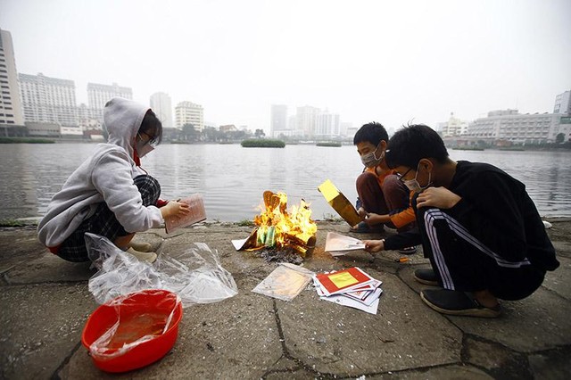 Một nhóm trẻ em trong một gia đình thay bố mẹ làm việc đốt vàng mã trước khi thả cá Một nhóm trẻ em trong một gia đình thay bố mẹ làm việc đốt vàng mã trước khi thả cá