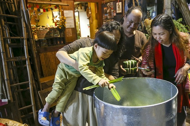 Con trai út 4 tuổi của anh Đức được mẹ bế lên xem công đoạn đặt bánh vào nồi Con trai út 4 tuổi của anh Đức được mẹ bế lên xem công đoạn đặt bánh vào nồi