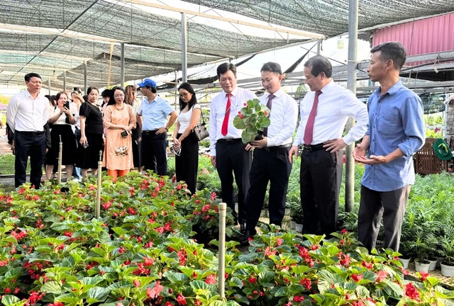 Ông Hoàng Văn Trào, Chủ tịch Hội Làm vườn xã Phúc Thọ (bìa phải) giới thiệu về vườn hoa, cây cảnh của gia đình. Ảnh: Hồ Hạ.