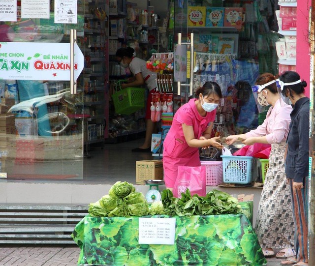 Nhân viên cửa hàng bán sản phẩm mẹ và bé tại TP.HCM bán rau, củ cho người dân (Ảnh: Lê Toàn).