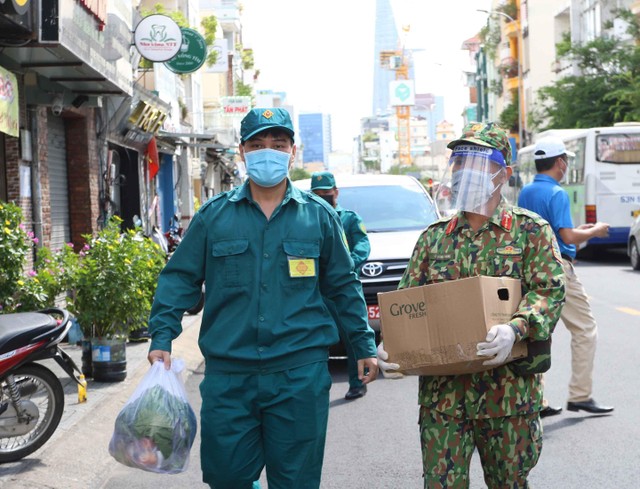 Lực lượng đi chợ thay người dân tìm địa chỉ nhà để giao hàng. (Ảnh: Lê Toàn).