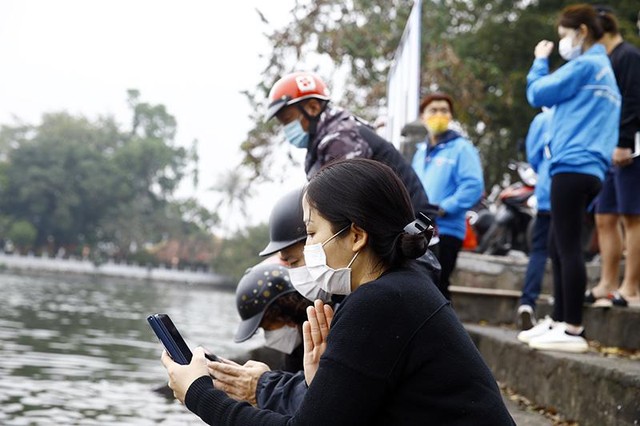 Là một phong tục, nhưng tùy theo sự hiểu của mỗi gia đình sẽ có cách cúng khác nhau, trong ảnh là đôi vợ chồng đang ngồi đọc bài khấn được chụp lại bằng điện thoại sau khi phóng sinh cá tại Hồ Tây