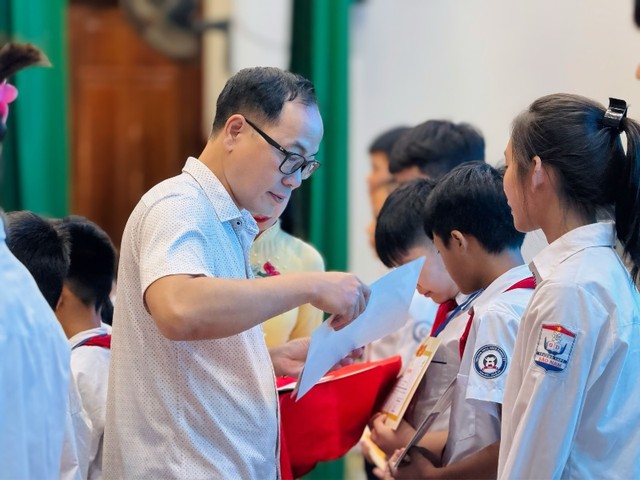 Ông Đặng Tuấn Khánh, Uỷ viên Ban biên tập Báo Đầu tư trao giấy chứng nhận và học bổng cho các em học sinh.