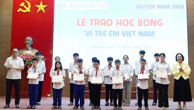 Bà Trần Kim Nga, Tổng giám đốc Công ty TNHH Việt Nam - Beverage và ông Đặng Tuấn Khánh, Uỷ viên Ban biên tập Báo Đầu tư trao học bổng và giấy chứng nhận cho các em học sinh.