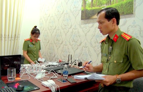 Công an kiểm đếm thiết bị điện tử tại nơi nhóm người Trung Quốc thuê để làm thẻ ATM giả và đánh bạc. Ảnh: Quang Bình.