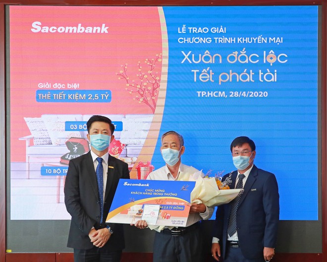  Ông Nguyễn Minh Tâm – Phó tổng giám đốc Sacombank (bên trái) trao sổ tiết kiệm trị giá 2,5 tỷ đồng cho khách hàng Hà Văn Thường (giữa), người may mắn trúng giải đặc biệt chương trình khuyến mãi “Xuân đắc lộc – Tết phát tài”.