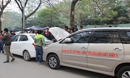 Tài xế dán khẩu hiệu với thông điệp yêu cầu Uber, Grab giảm chiết khấu lên thân xe. Ảnh: Anh Tú