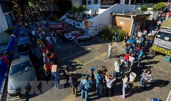 Người dân Venezuela xếp hàng chờ đổi tiền bên ngoài ngân hàng trung ương ở Caracas. (Nguồn: AFP/TTXVN).