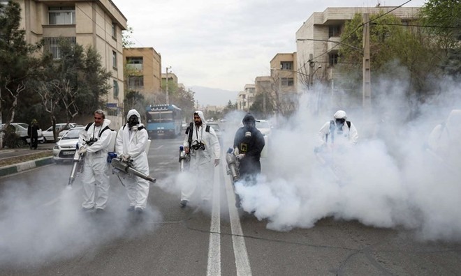 Nhân viên cứu hỏa trong trang phục bảo hộ khử trùng đường phố ở thủ đô Tehran, Iran, ngày 18/3. Ảnh: Reuters.