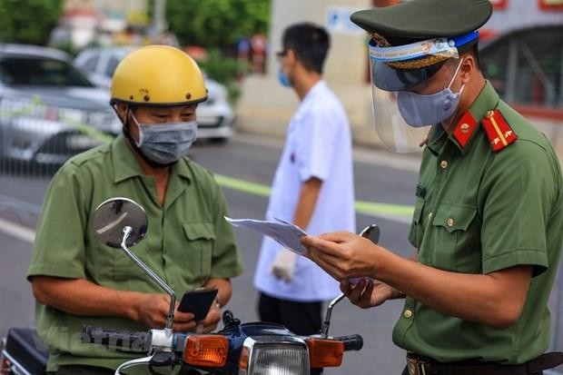 Trên tuyến đường Cầu Diễn (Bắc Từ Liêm, Hà Nội), lực lượng chức năng đã lập hàng rào chia thành 2 làn đường để tiến hành kiểm soát. Ngày hôm nay, Tổ công tác sẽ tiến hành tuyên truyền cho người dân về quy định mới trong Chỉ thị 20 đã áp dụng để chống dịch. (Ảnh: Minh Sơn/Vietnam+).