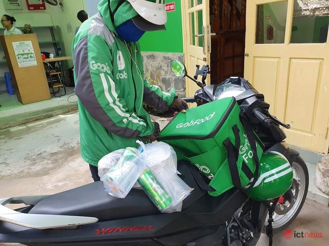 Một tài xế GrabFood bịt khẩu trang khi đi giao hàng.Ảnh: Vietnamnet