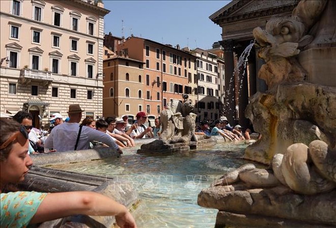 Khách du lịch tránh nóng bên đài phun nước tại Rome, Italy, ngày 18/7/2023. Ảnh: THX/TTXVN