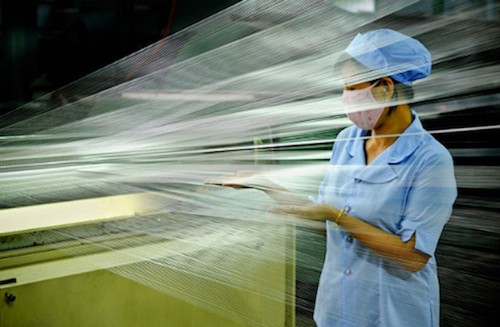 Công nhân kiểm tra chất lượng sợi trên dây chuyền sản xuất.