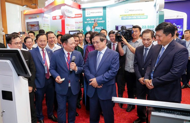 Thủ tướng Chính phủ Phạm Minh Chính thăm và lắng nghe ông Hoàng Minh Ngọc, Phó tổng giám đốc Agribank giới thiệu về hoạt động số của Agribank.