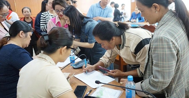 Người dân phấn khởi điền thông tin hộ gia đình để nhận quà Tết Độc lập. Ảnh: Hương Lý.