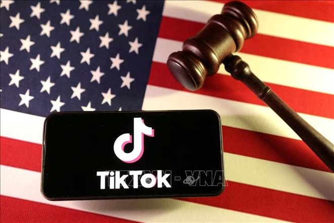 Logo của ứng dụng TikTok trên điện thoại và quốc kỳ Mỹ. Ảnh: Reuters/TTXVN