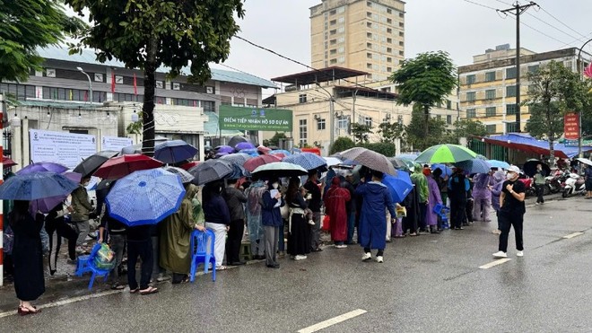 Người dân "đội mưa" xếp hàng nộp hồ sơ mua nhà ở xã hội.