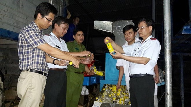 Đoàn thanh tra cùng đại diện Công ty URC Hà Nội giám sát việc tiêu hủy hàng không đạt chất lượng. (Ảnh: BYT cung cấp)