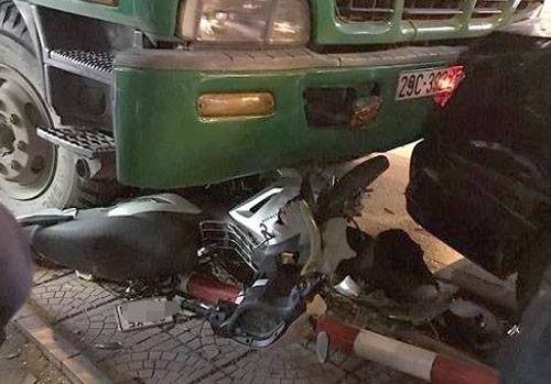 Xe máy chở hai người đàn ông bị xe rác cuốn vào gầm và hư hỏng nặng. Ảnh: Bảo Sơn.