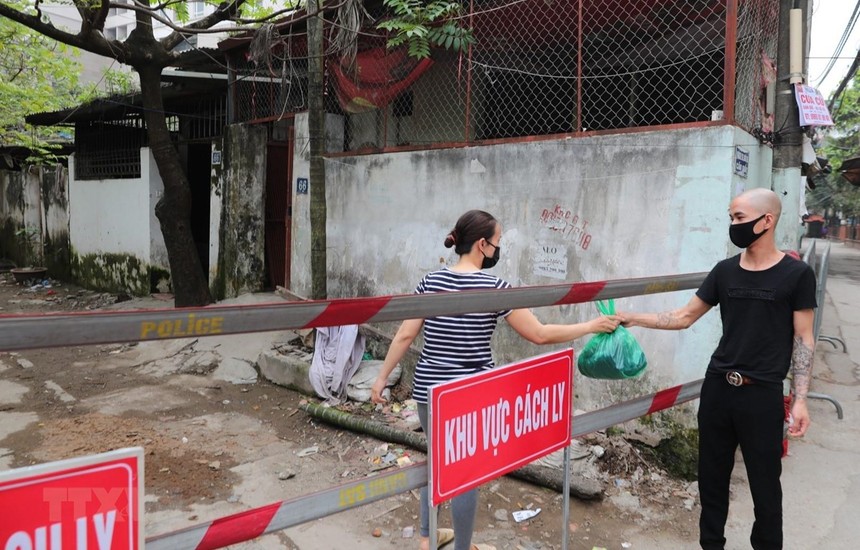 Người thân chuyển nhu yếu phẩm cho người trong khu vực cách ly ngõ 165 Cầu Giấy. (Ảnh: Thành Đạt/TTXVN).