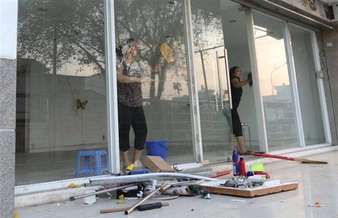 Cư dân block A, chung cư Carina Plaza trở về thu dọn để mở cửa lại quán cà phê Yuki ở tầng 1. (Ảnh: Thanh Vũ/TTXVN).
