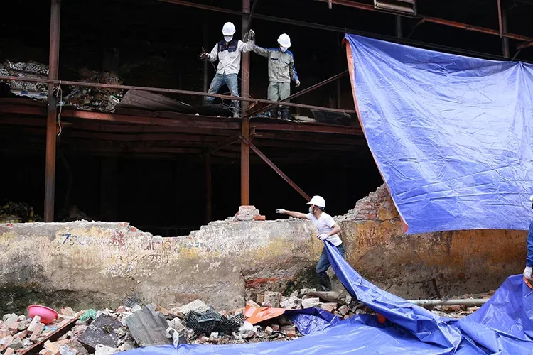 Công nhân quây bạt che kín khu vực hiện trường vụ cháy, hạn chế ảnh hưởng ra xung quanh. Ảnh: Tất Định.