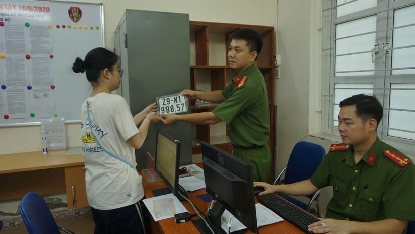 Lực lượng công an cấp biển số xe máy cho người dân đến đăng ký, bấm biển (Ảnh: Hoàng Hiệp).