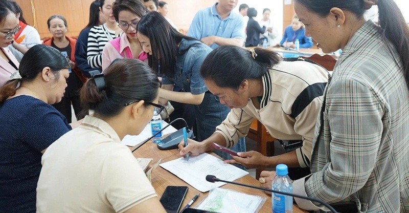 Người dân phấn khởi điền thông tin hộ gia đình để nhận quà Tết Độc lập. Ảnh: Hương Lý.